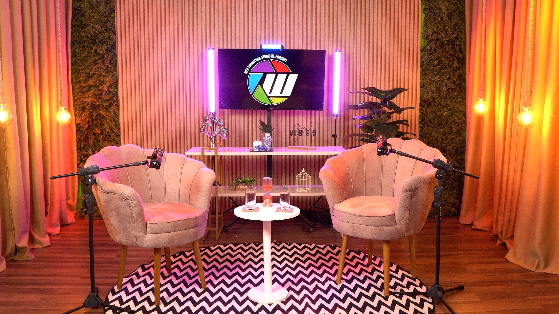 Cenário com poltronas rosa e credenza com TV