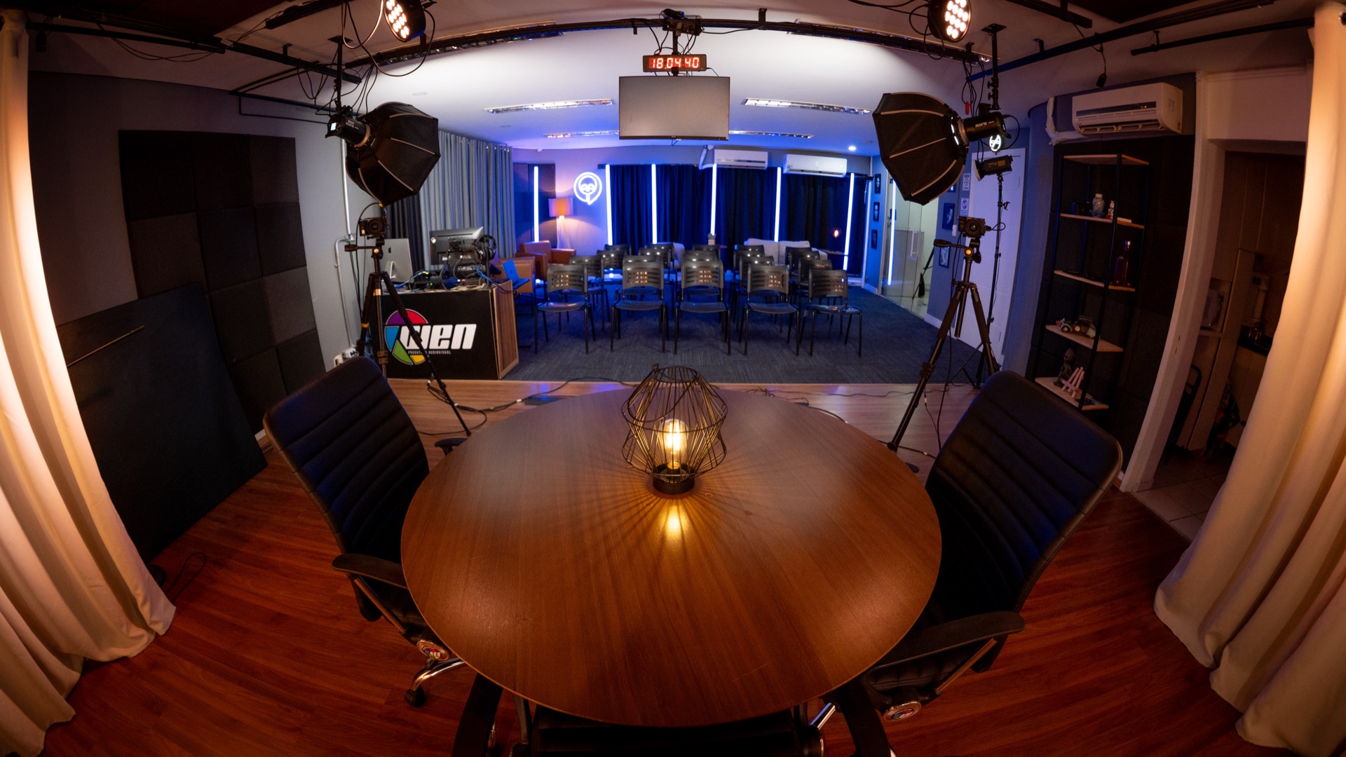 Mesa de podcast com platéia ao fundo no Studio B